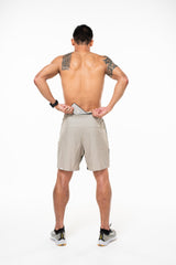 Model placing phone in back pocket of Sand/Black Noosa Run Short. Lined running shorts with pockets