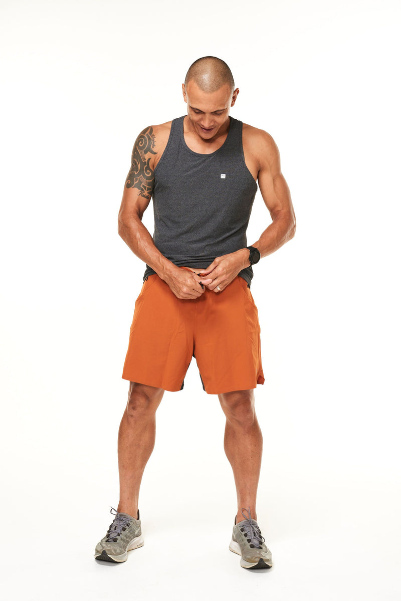 Model tying the drawstring in his rust Rep Shorts. Men's gym shorts with a drawstring for a comfortable fit.
