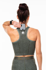 Model placing phone in back pocket of Panther Cheetah Core Crop. Women's running top with pockets.